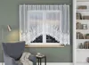 A white lace curtain hangs over a window in a room with a gray armchair and a bookshelf. Náhled obrázku produktu