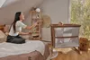 A woman is playing with a baby in a nursery room. The baby is in a crib, and the woman is sitting on the bed. Náhľad obrázku produktu