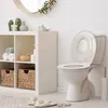 A clean and organized bathroom with a toilet, storage shelves, and decorative items. Produktbild-Vorschau