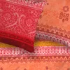 A close-up view of a patterned textile, likely bedding, with intricate designs in red, orange, and yellow hues. Produktbild-Vorschau