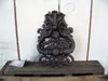 A dark brown, ornate cast iron door knocker is displayed against a white wooden plank background, resting on a weathered wooden surface. Produktbild-Vorschau