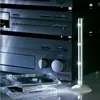 A stack of CD cases in front of audio equipment, with a slim LED light standing to the right. Podgląd zdjęcia produktu