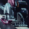 Close-up of a circular saw being held by a person, with a focus on the blade and cutting guide. Náhled obrázku produktu