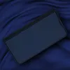 A dark blue flip cover case for a smartphone, resting on a dark blue fabric with folds. Produktbild-Vorschau