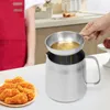 A person is using a stainless steel oil strainer pot in a kitchen setting, with fried chicken on a plate in the foreground. Podgląd zdjęcia produktu