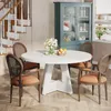 A dining set with a round white table and four chairs in a room with a staircase and a cabinet. Náhľad obrázku produktu