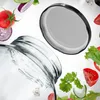 A close-up view of a glass jar with a lid and various vegetables floating around it. Voir les images du produit