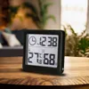 A digital thermometer and hygrometer with a clock function sits on a wooden table. Anteprima dell’immagine prodotto