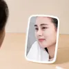 A woman is looking into a lighted makeup mirror, holding a white towel to her face. Podgląd zdjęcia produktu