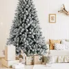 A festive Christmas scene with a flocked artificial tree, gifts, and a sofa in the background. Produktbild-Vorschau