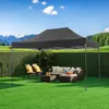 An outdoor patio scene with a gray canopy tent set up over a wicker furniture set on a green lawn, with a backdrop of manicured hedges and distant mountains under a blue sky. Voir les images du produit
