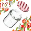 A clear glass jar with a red and white checkered lid, surrounded by fresh vegetables and herbs. Produktbild-Vorschau