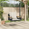A hanging chair with cushions is shown on a wooden deck in a garden setting. Náhled obrázku produktu