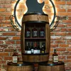 A wooden barrel-shaped wine cabinet filled with bottles of alcohol, set against a brick wall with a decorative guitar silhouette. Náhled obrázku produktu