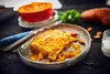 A close-up of a prepared dish with ingredients in the background. Produktbild-Vorschau