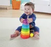 A baby sitting on a carpet playing with a stacking toy. Produktbild-Vorschau