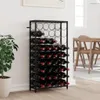 A black metal wine rack filled with wine bottles, placed against a white wall next to a potted plant. A dining table and chairs are visible in the background. Produktbild-Vorschau
