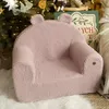 A pink teddy bear-shaped children's chair is placed in front of a decorated Christmas tree. Produktbild-Vorschau