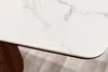 A close-up view of the edge of a white marble-patterned tabletop with a dark brown edge, resting on a wooden leg. The background shows a light wood-patterned floor. Produktbild-Vorschau