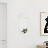 A minimalist interior scene with a mirror and a framed picture on a white wall. Produktbild-Vorschau