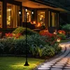 A garden lamp post with three lights illuminates a garden path and flower beds at dusk. Produktbild-Vorschau