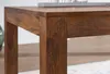 A close-up view of the corner and leg of a wooden dining table. Náhľad obrázku produktu