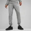 A person wearing grey Puma sweatpants and black sneakers against a light grey background. Anteprima dell’immagine prodotto