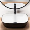 A black and white rectangular vessel sink with a black faucet is shown on a wooden surface, with a mirror reflecting the scene. Náhled obrázku produktu