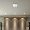 A white ceiling-mounted motion sensor is shown against a neutral ceiling. Náhľad obrázku produktu