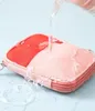 Water being poured onto a pink and red pouch, demonstrating its water-resistant properties. Náhľad obrázku produktu