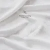 A close-up of a white, soft fabric, possibly a bedsheet or blanket, with a feather resting on it. Text overlay indicates the fabric is soft and cozy. Produktbild-Vorschau