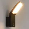 A modern black LED outdoor wall light with a motion sensor, mounted on a light gray wall. Produktbild-Vorschau