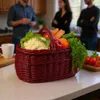 A red woven basket filled with fresh vegetables and fruits sits on a kitchen counter, with two people in the background. Náhled obrázku produktu
