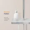 A close-up of a modern shower system with a soap dispenser on a shelf and water flowing from the showerhead. Produktbild-Vorschau