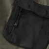A close-up view of a black zippered pocket on an olive green garment. Podgląd zdjęcia produktu