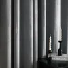 Two black candle holders with white spiral candles are placed on a black surface in front of gray curtains. A book with the text "REDSTAR" is visible under the candle holders. Produktbild-Vorschau