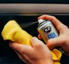 Hands spraying a cleaning product onto a yellow microfiber cloth. Podgląd zdjęcia produktu