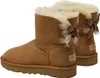 Two brown Ugg boots with cream lining and brown bows on the back. Produktbild-Vorschau