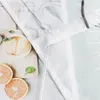 A close-up view of a white fabric curtain with a gray embroidered edge, placed over a background with images of ice cream and grapefruit slices. Produktbild-Vorschau