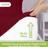 A hand is stretching a burgundy fitted sheet over a mattress. Produktbild-Vorschau
