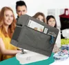A sewing machine cover with pockets filled with sewing supplies, in front of a group of people. Produktbild-Vorschau