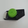 A close-up view of a small electronic component with a green dial and a white connector. Produktbild-Vorschau