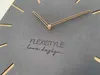 A close-up view of a modern wall clock with a gray face and rose gold hands. Náhled obrázku produktu