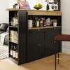 A modern bar cabinet with a rotating top, stocked with bottles and glasses, set in a living room environment next to a sofa. Voir les images du produit