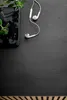 A smartphone and earbuds are placed on a dark, textured surface next to a plant. Náhled obrázku produktu