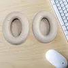 Two ear pads for headphones are placed on a wooden desk next to a computer keyboard and mouse. Produktbild-Vorschau