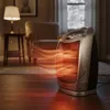 A ceramic heater is shown in a cozy living room setting, emitting warm orange heat waves. Podgląd zdjęcia produktu