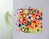 A colorful floral puzzle is partially assembled on a light gray surface, with scattered puzzle pieces around it. A light green curved object is visible on the left side of the image. Produktbild-Vorschau