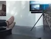 A person's feet are propped up on a table in front of a TV on a tripod stand. Anteprima dell’immagine prodotto