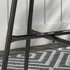Close-up of the black metal legs of a table on a patterned rug. Produktbild-Vorschau